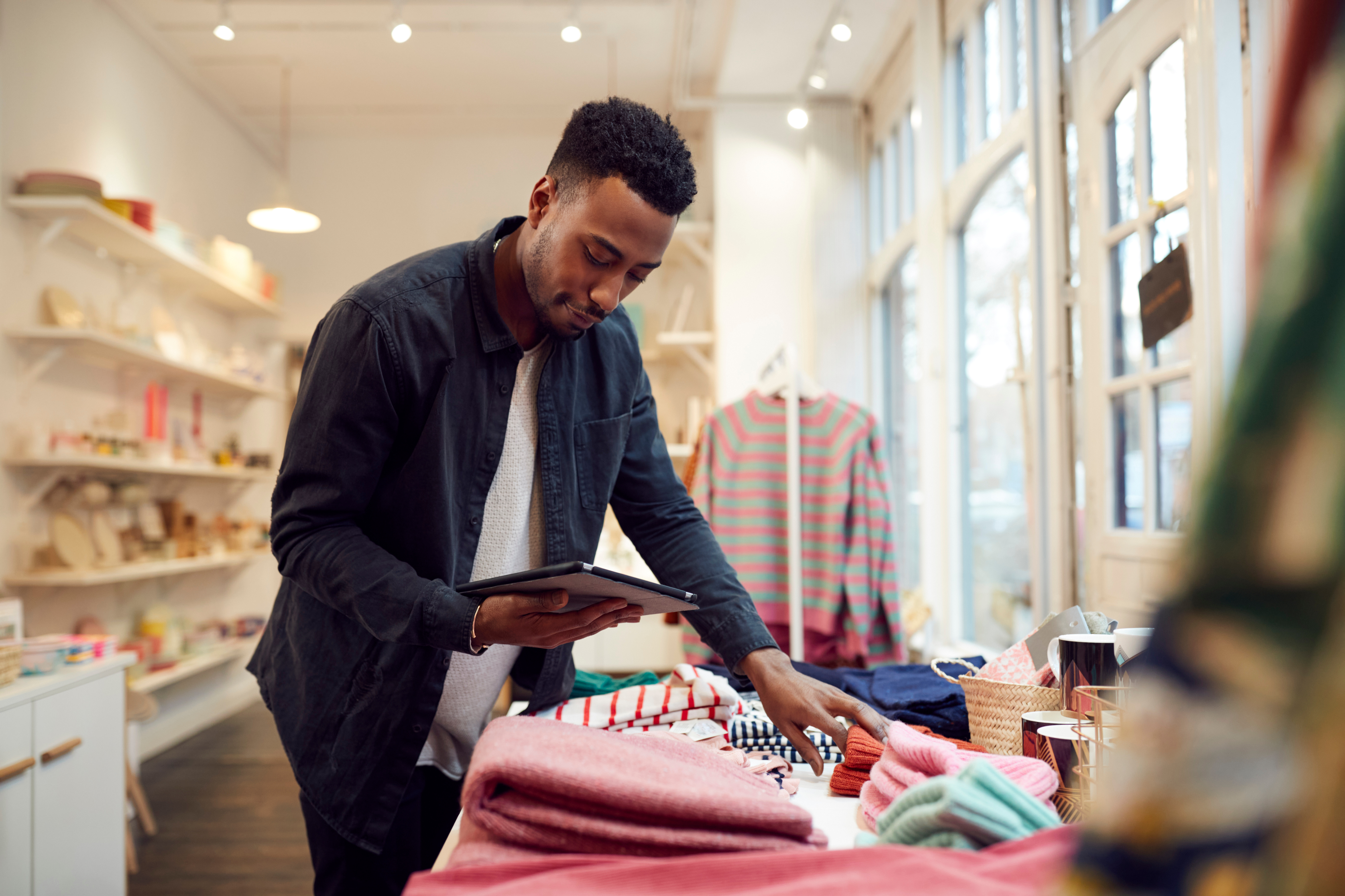 Male Small Business Owner Checks Stock In Shop Using Digital Tablet Male Small Business Owner Checks Stock In Shop Using Digital Tablet
