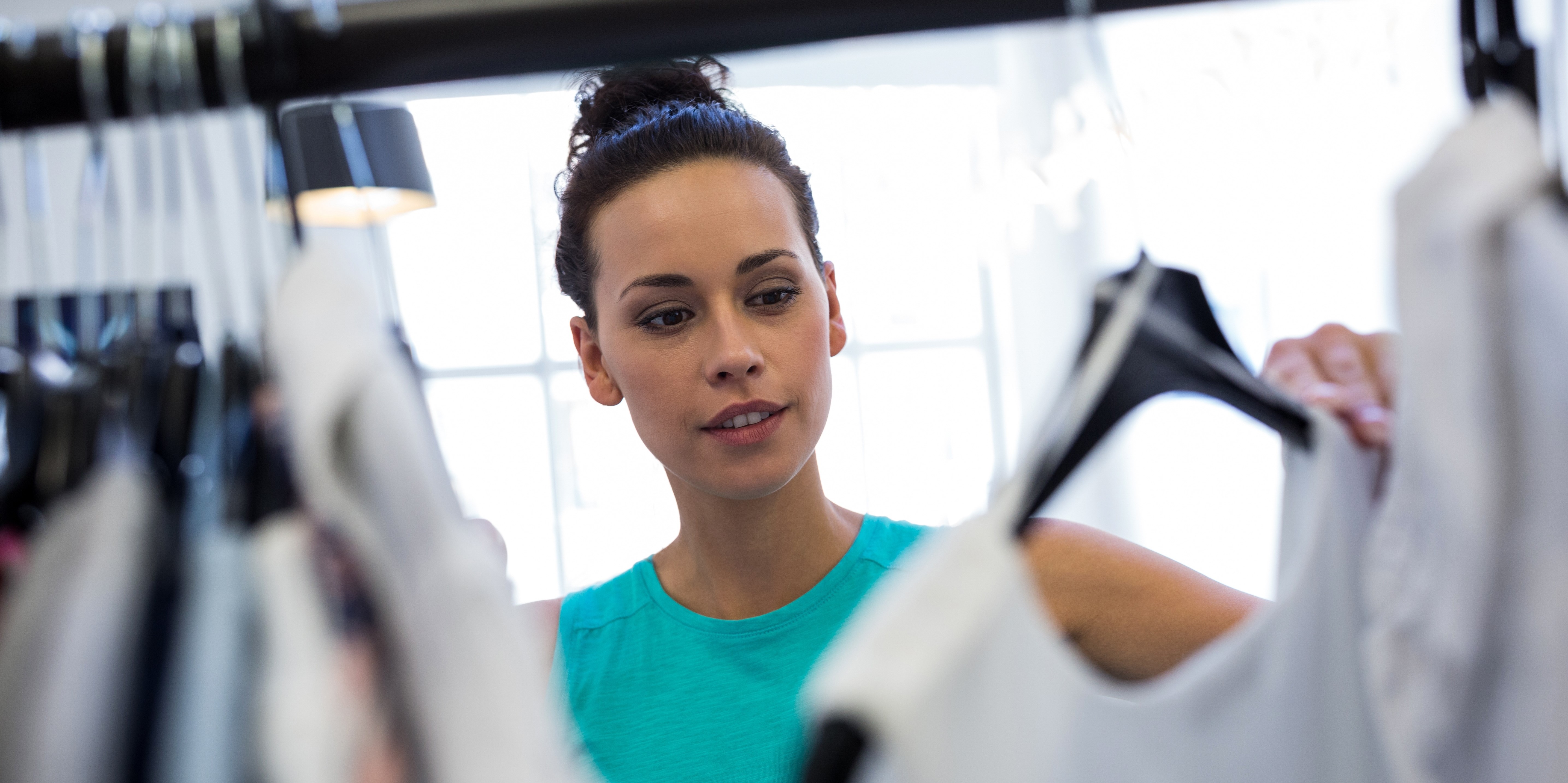 Female sales associate peruses clothing rack. Female sales associate peruses clothing rack.