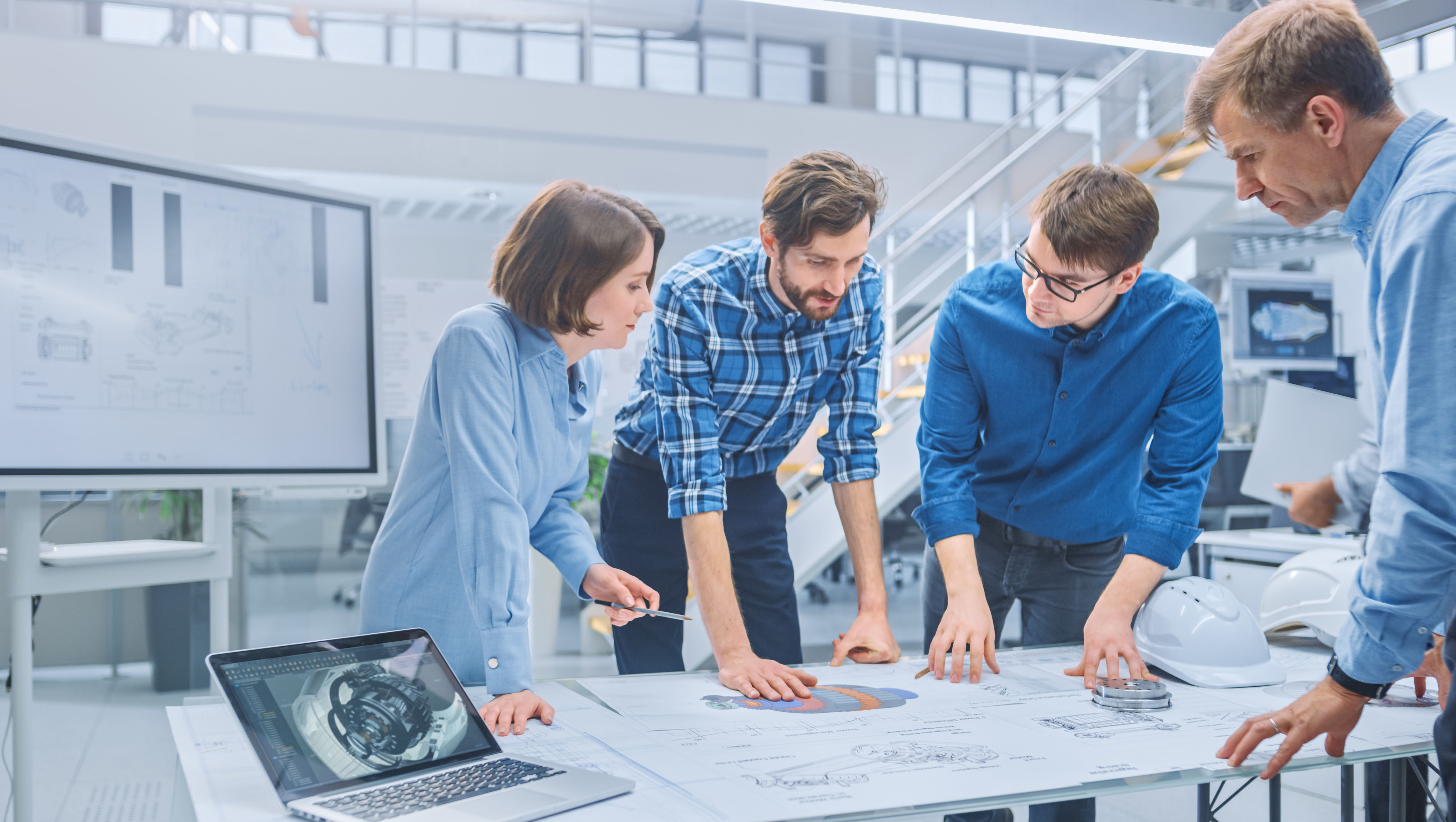 In the Industrial Engineering Facility: Diverse Group of Engineers and Technicians on a Meeting Gather Around Table with Engine Design Technical Drafts, Have Discussion, Analyse Technology In the Industrial Engineering Facility: Diverse Group of Engineers and Technicians on a Meeting Gather Around Table with Engine Design Technical Drafts, Have Discussion, Analyse Technology