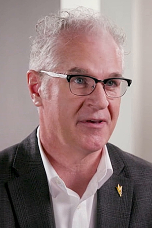 Professional headshot of a man in a suit and glasses