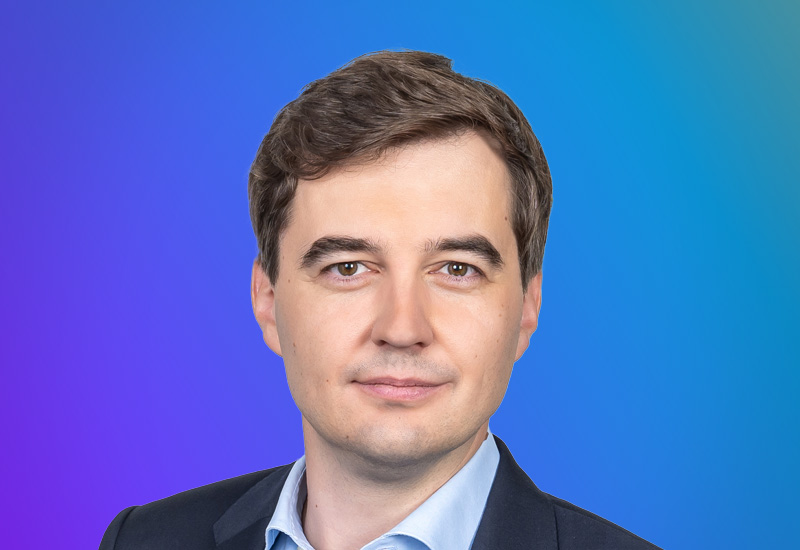 Professional headshot of a person in business attire with a gradient blue and purple background, used for the AWS Summit Hamburg event.