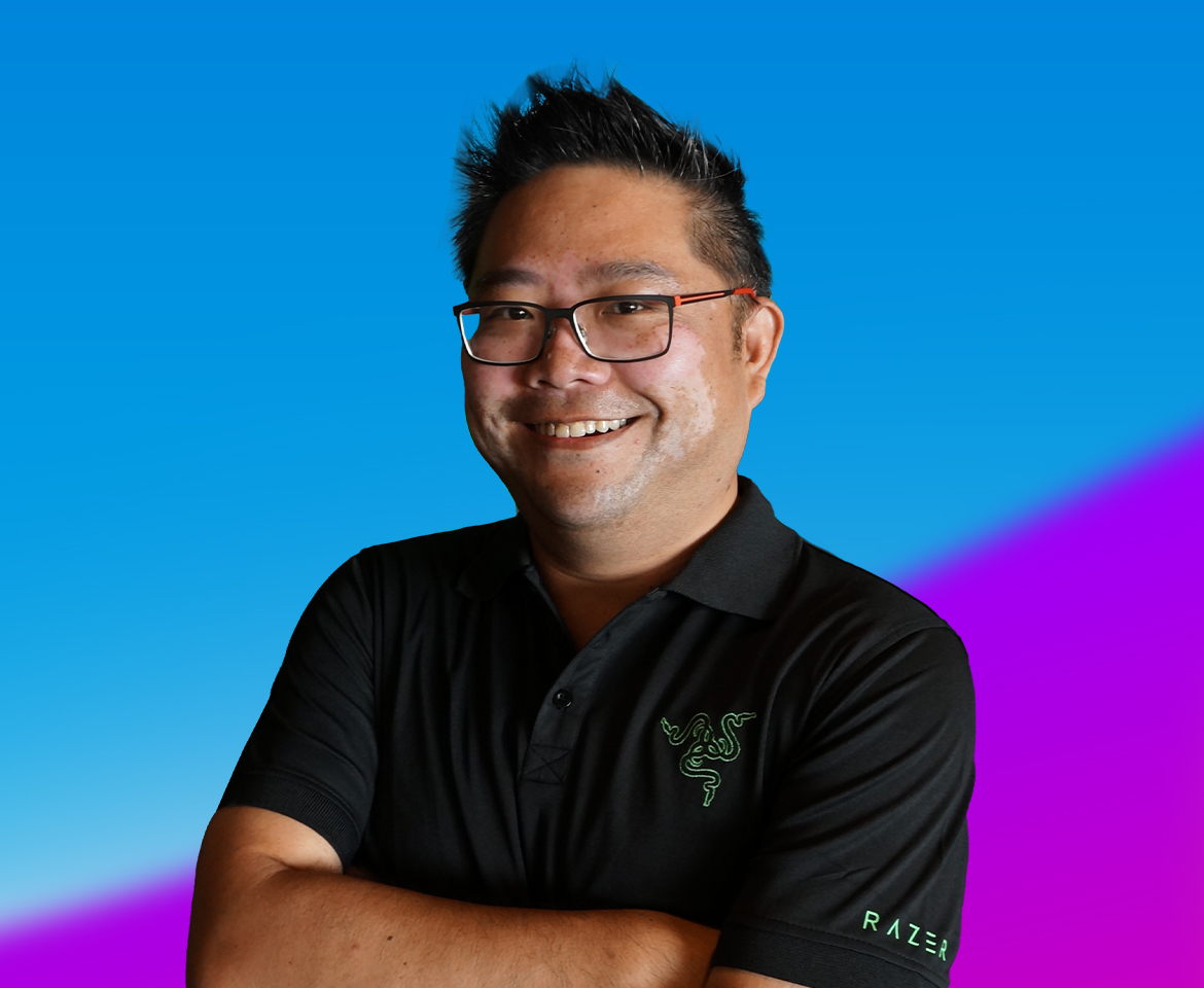 A person wearing a black Razer polo shirt with arms crossed, set against a vibrant blue and purple gradient background.