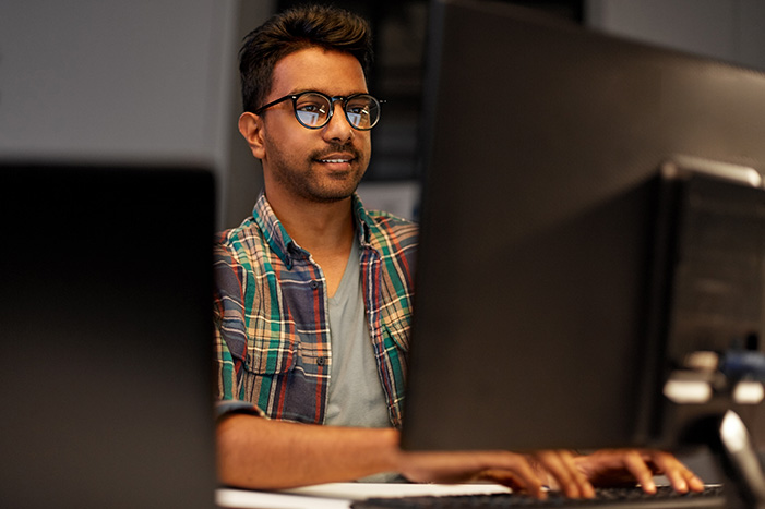 deadline, technology and people concept - close up of creative man in glasses working at night office and thinking