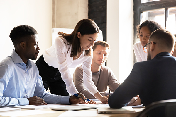 Diverse colleagues working on project together, sitting at table in boardroom, working with legal documents, financial report with statistics, employees engaged in teamwork at corporate meeting