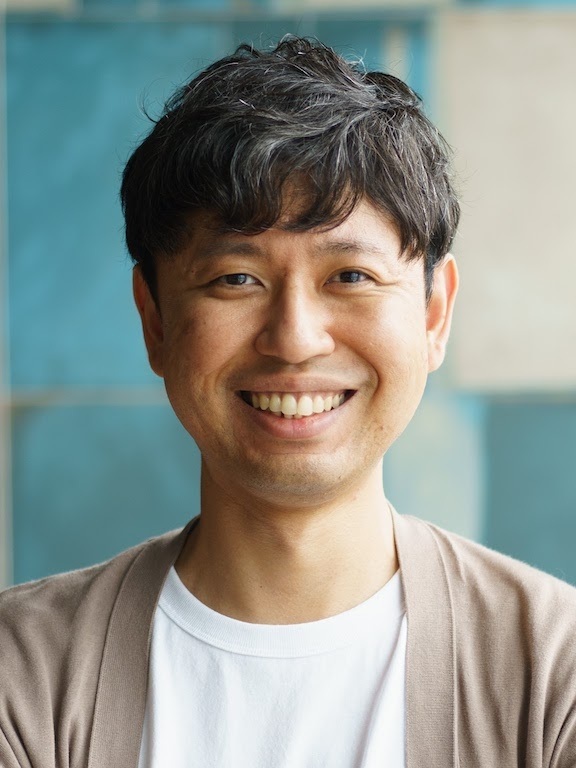 Portrait of a smiling man in casual attire against a blue background