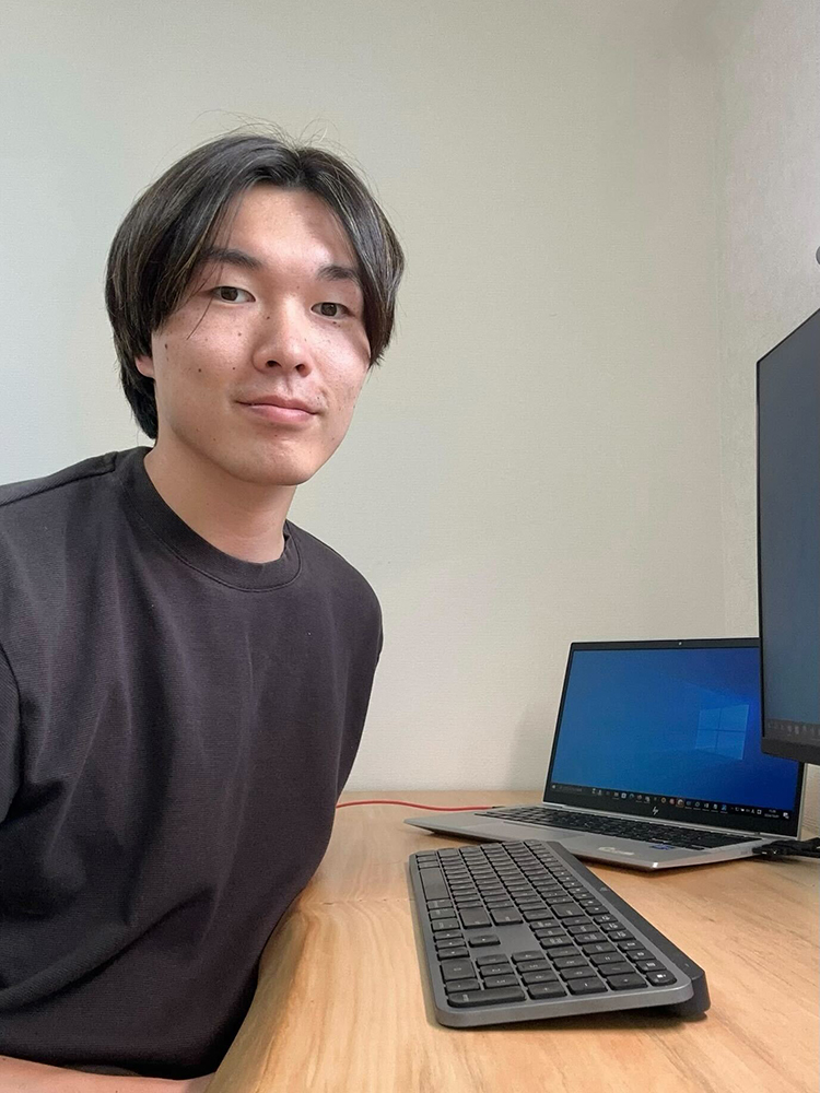 A person sitting at a desk with a laptop, external keyboard, and monitor.