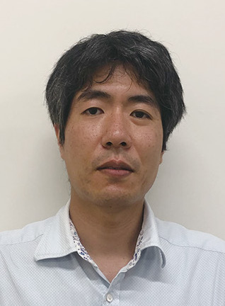 Portrait of a man in a light blue collared shirt against a plain background