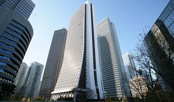 A modern high-rise office building, home to Sompo Holdings, surrounded by other skyscrapers in a cityscape under a clear blue sky. This image is used for an AWS case study related to Sompo Holdings.