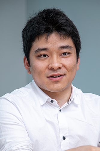 Portrait photograph of a person in a white shirt, pictured against a soft background. This image is associated with Softbrain's Miyata for a solution case study on the AWS Japan website.