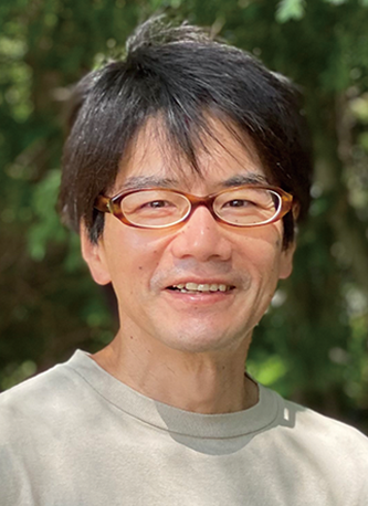 Portrait of a man wearing glasses outdoors, with a background of greenery. Associated with Hoshino Resorts.