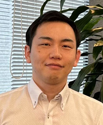 Portrait of a man in a light shirt, standing indoors in front of blinds and green plants. This image appears to be used for a case study related to Toda Kensetsu Miyaji Hiroto.